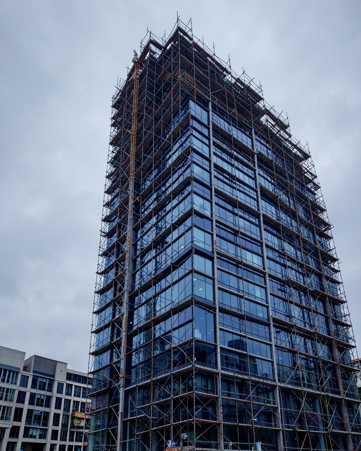 Commercial high-rise envelope under construction with scaffolding