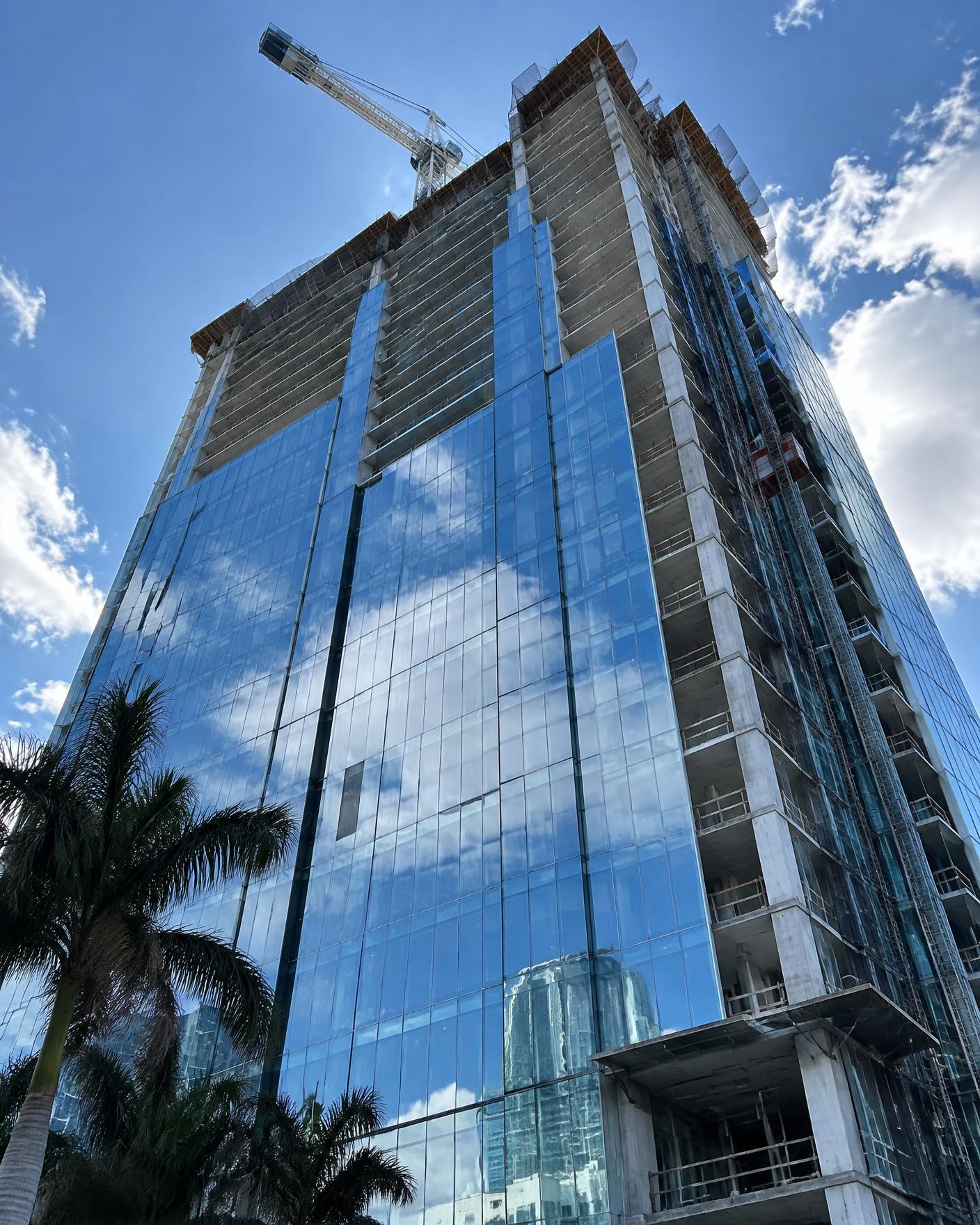 Glass high-rise tower under construction with a tower crane above